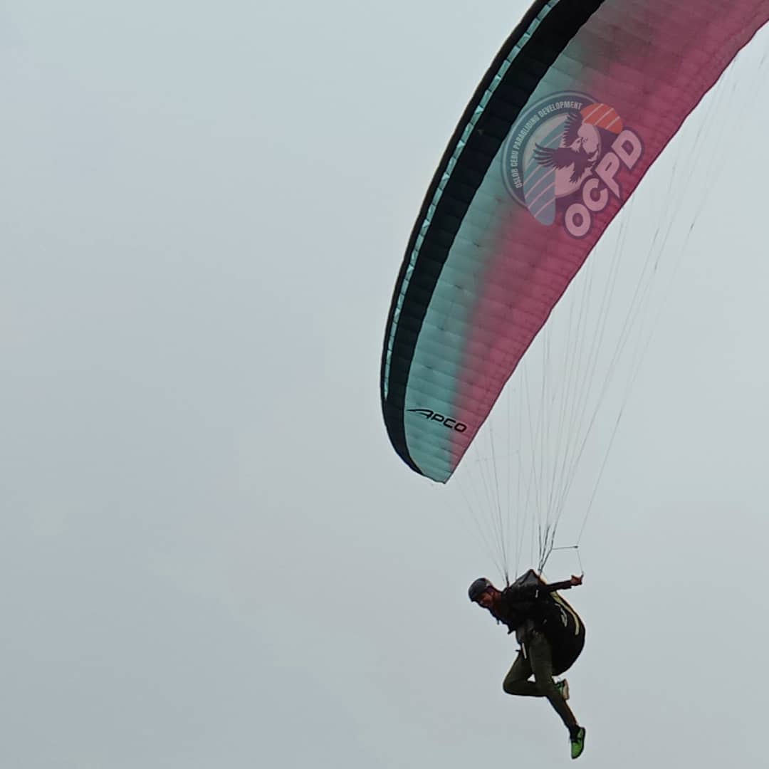 Paraglider soaring solo over Oslob mountains